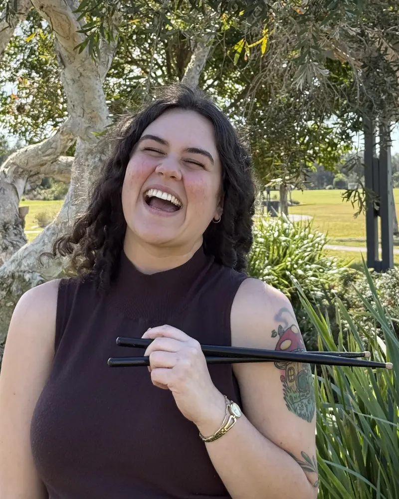 Steph, speech pathologist, laughing and holding chopsticks